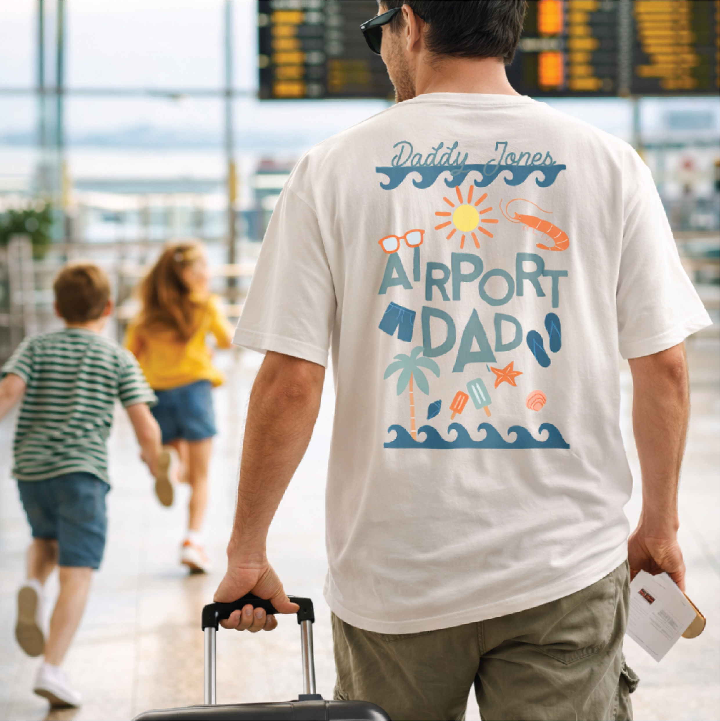 Man wearing a 'Airport Dad' t-shirt in an airport with children in the background.