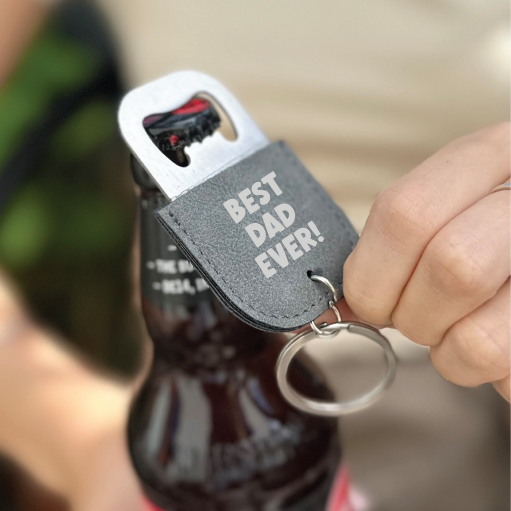Keychain bottle opener with 'Best Dad Ever!' text held by a hand over a bottle.
