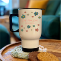 White travel mug with floral designs and text on a wooden surface