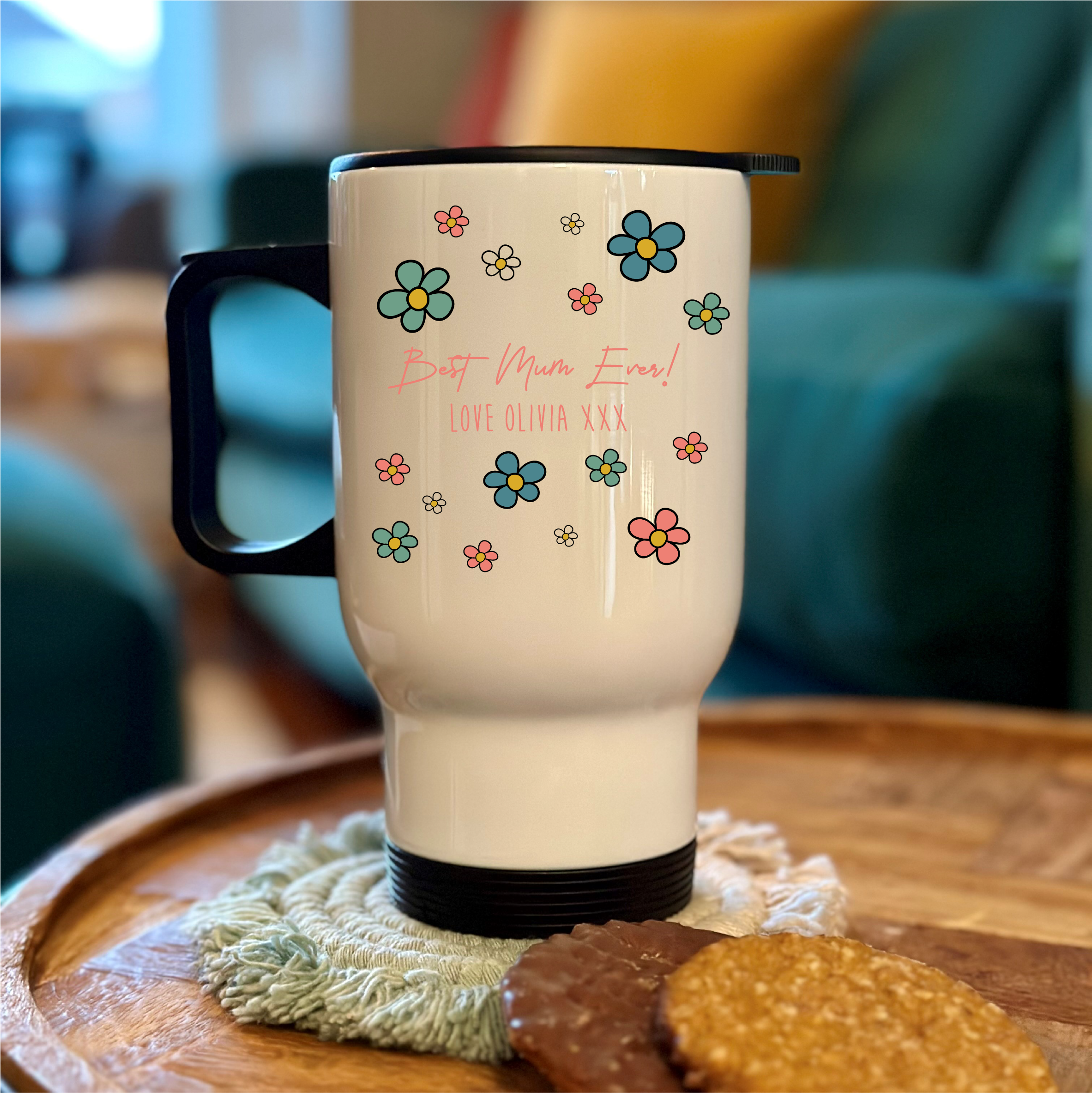 White travel mug with floral designs and text on a wooden surface