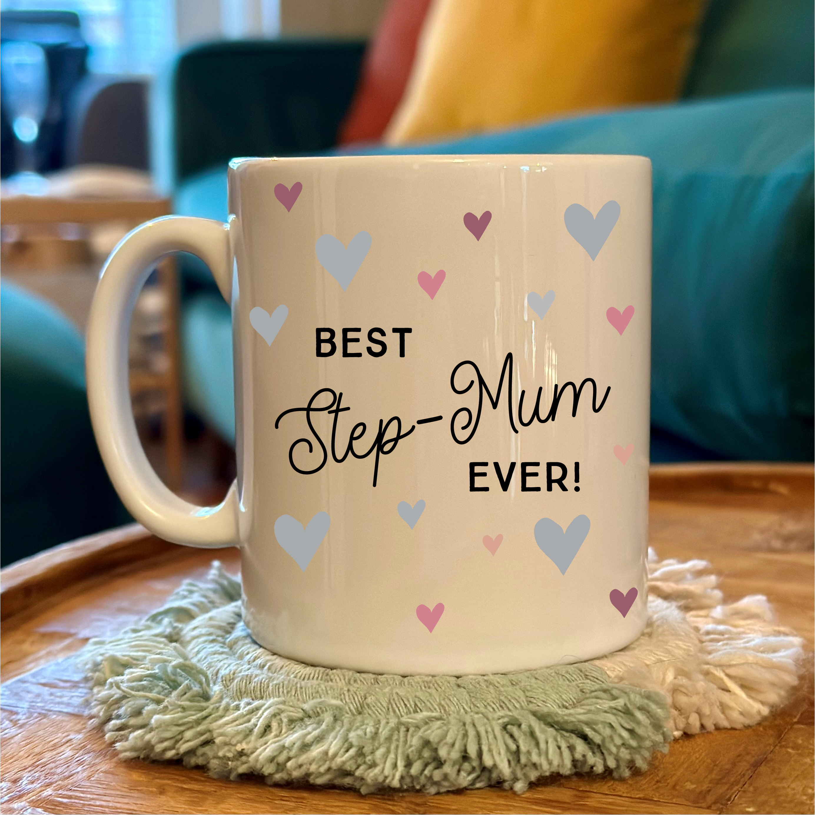 Mug with 'Best Step-Mum Ever!' text on a wooden table with a cozy background