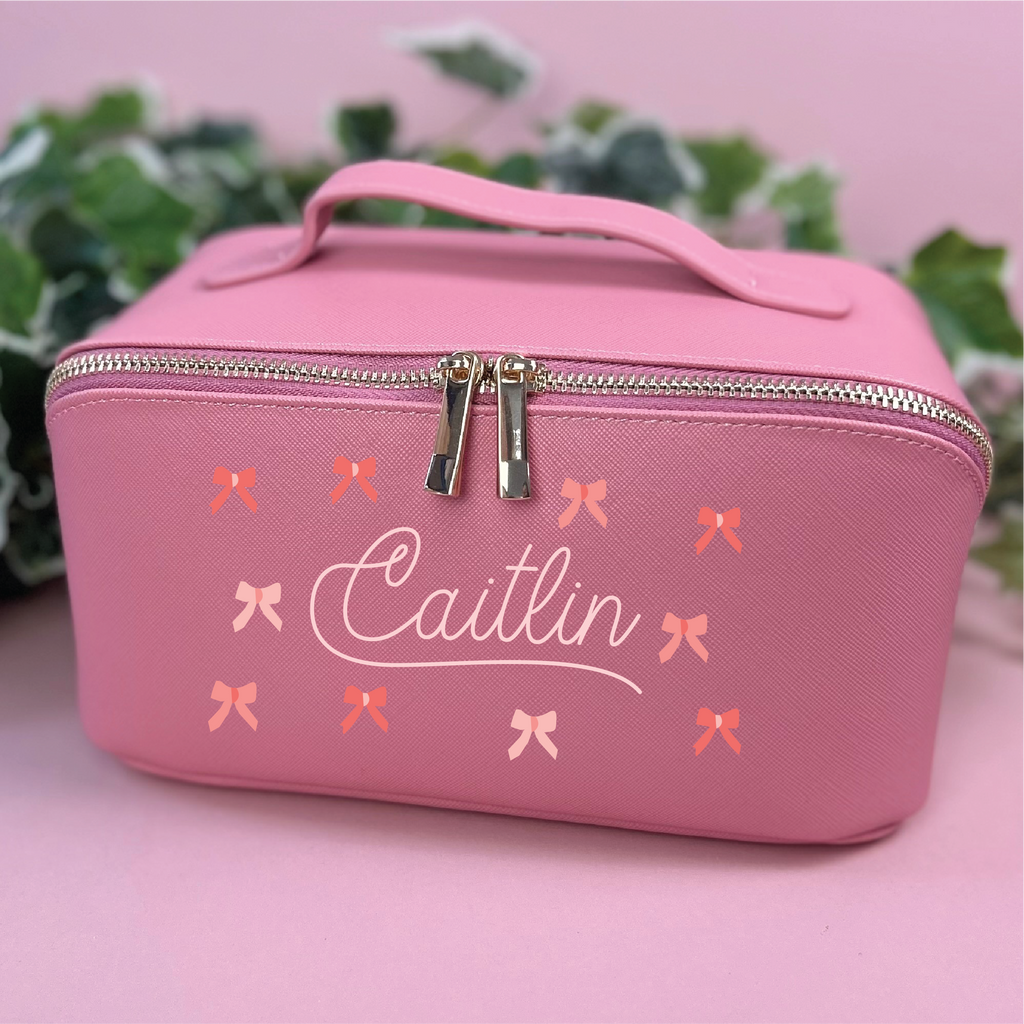 Pink cosmetic bag with 'Caitlin' and bow designs on a pink background