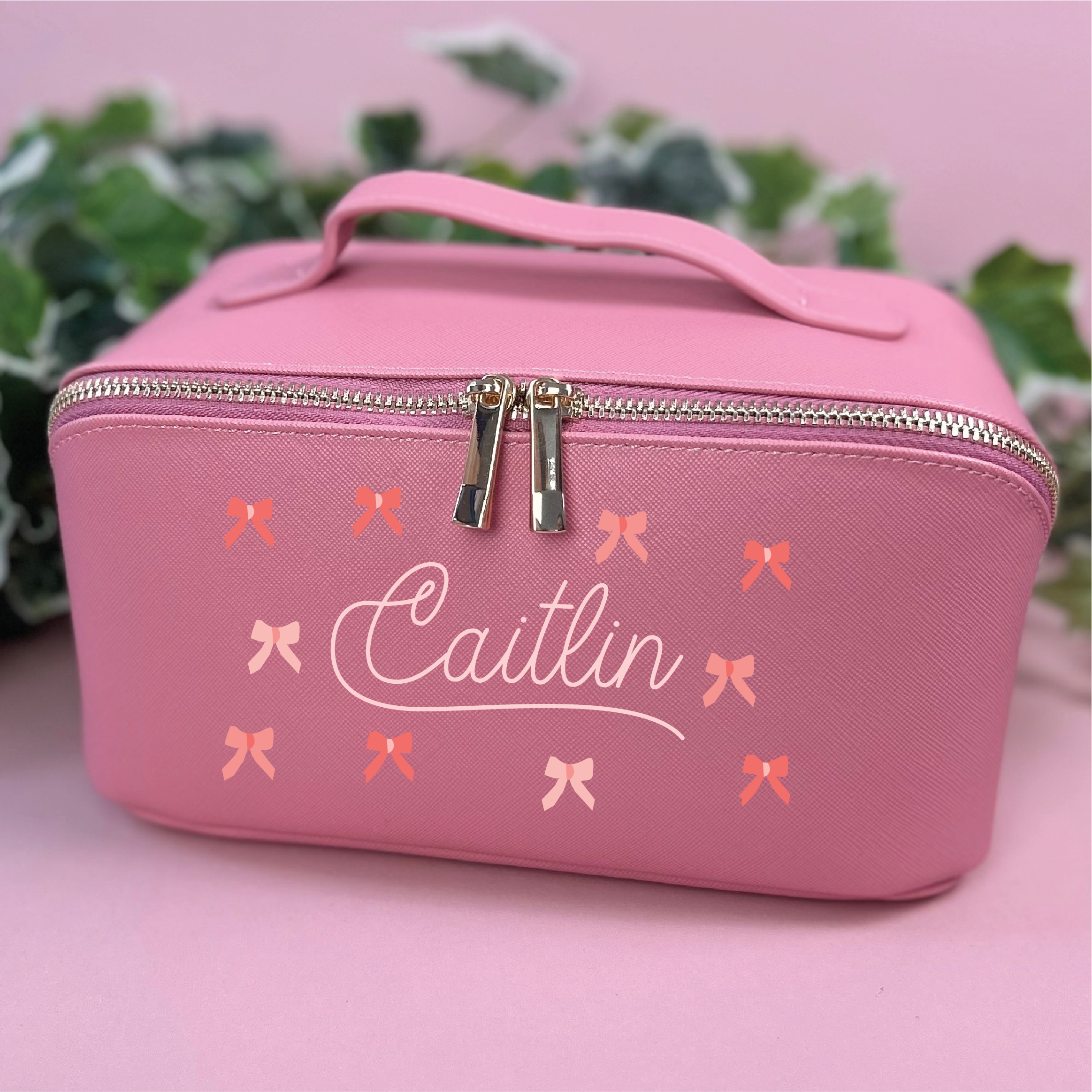 Pink cosmetic bag with 'Caitlin' and bow designs on a pink background