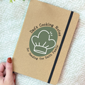 Notebook titled 'Dad's Cooking Notes' held by a hand on a textured surface