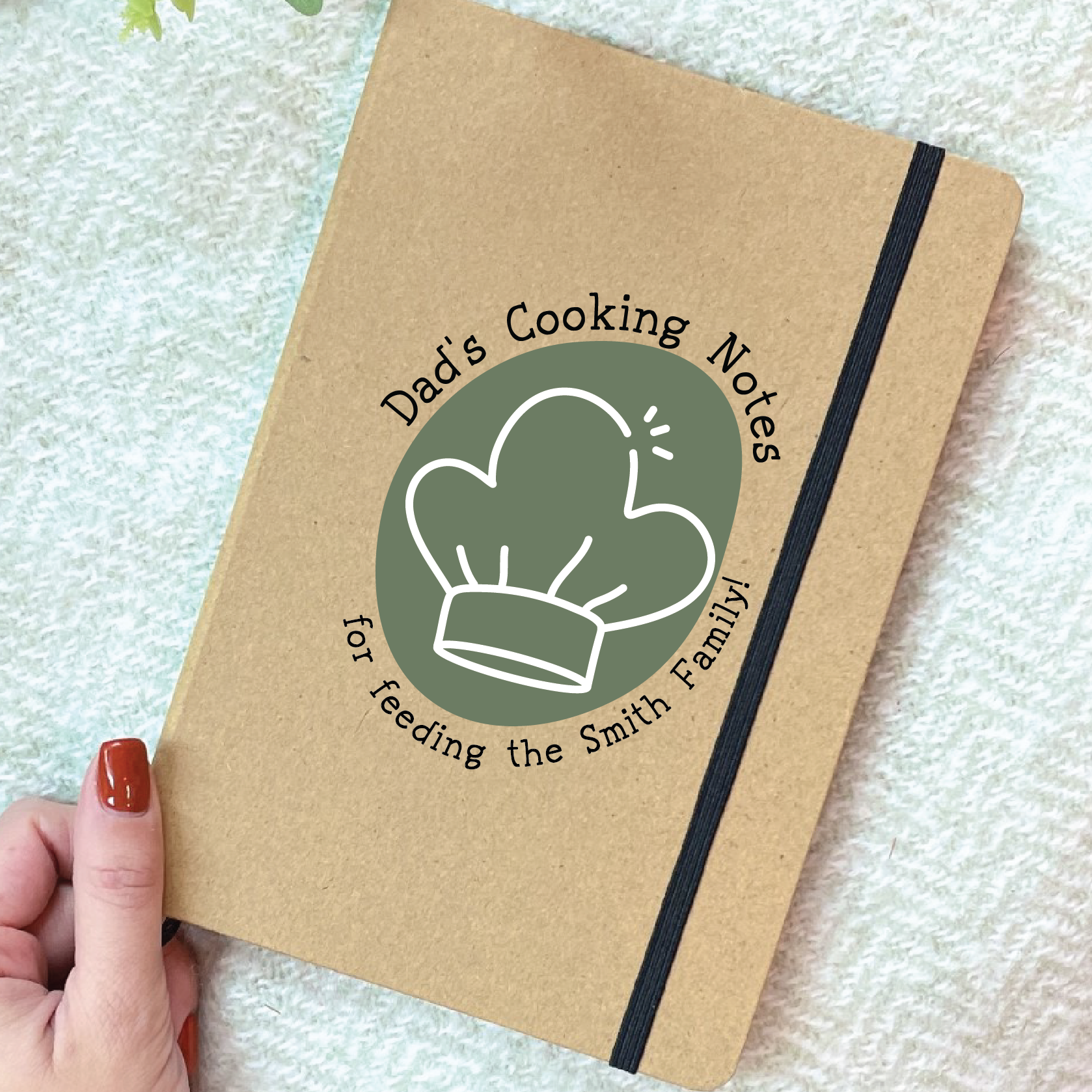 Notebook titled 'Dad's Cooking Notes' held by a hand on a textured surface