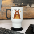 White travel mug with a bear illustration and 'Daddy Bear' text on a wooden desk.