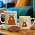 Two bear-themed mugs on a table with a blurred background