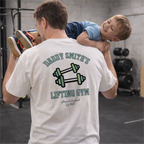 Man lifting a child on his shoulders with a 'Daddy Smith's Lifting Gym' t-shirt in a gym setting.