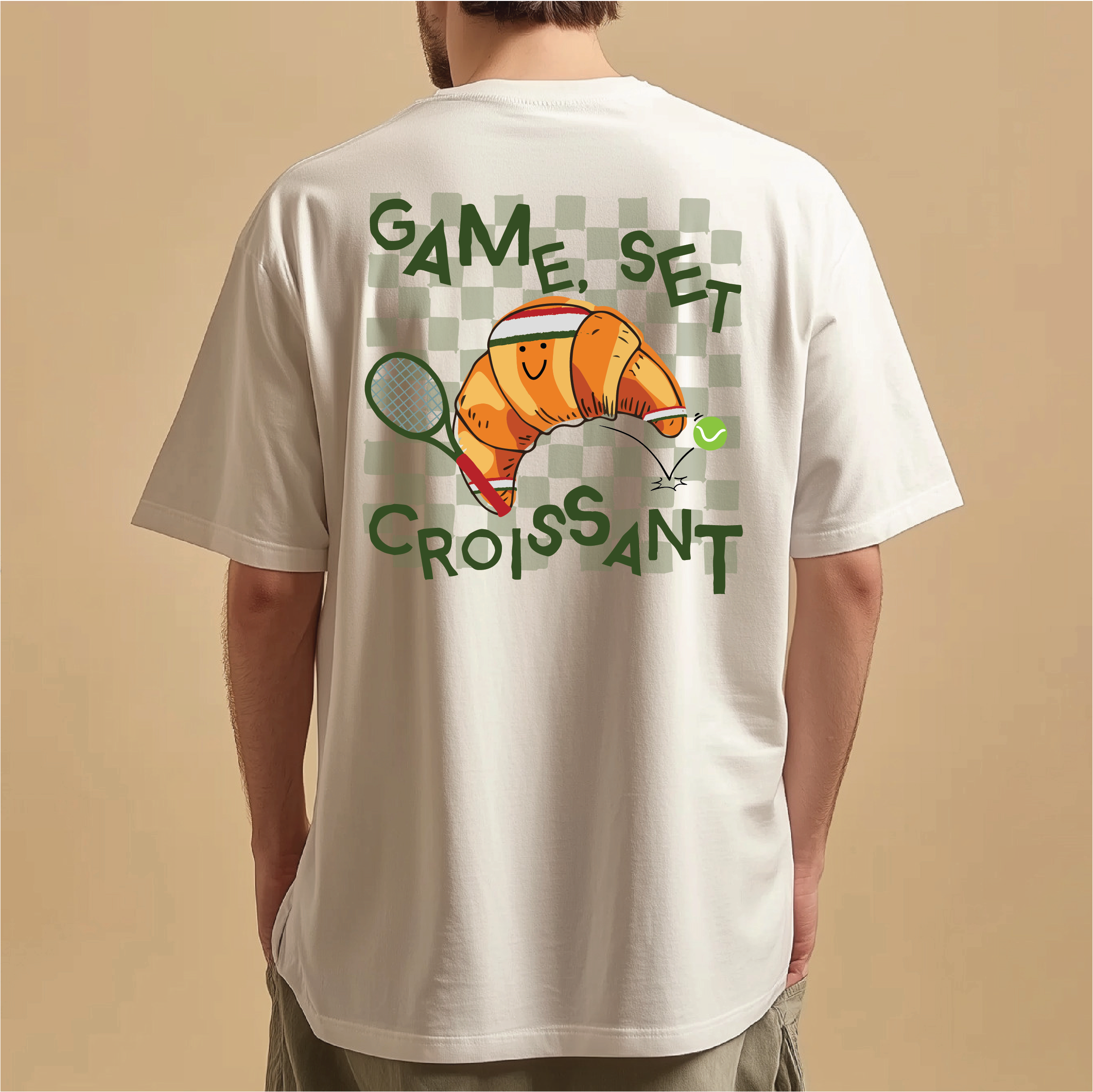 White t-shirt with a croissant graphic and text on the back, worn by a person against a beige background.