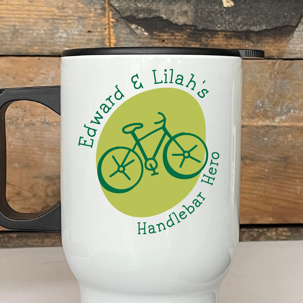 White travel mug with bicycle design and text on a wooden surface
