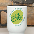 White travel mug with bicycle design and text on a wooden surface