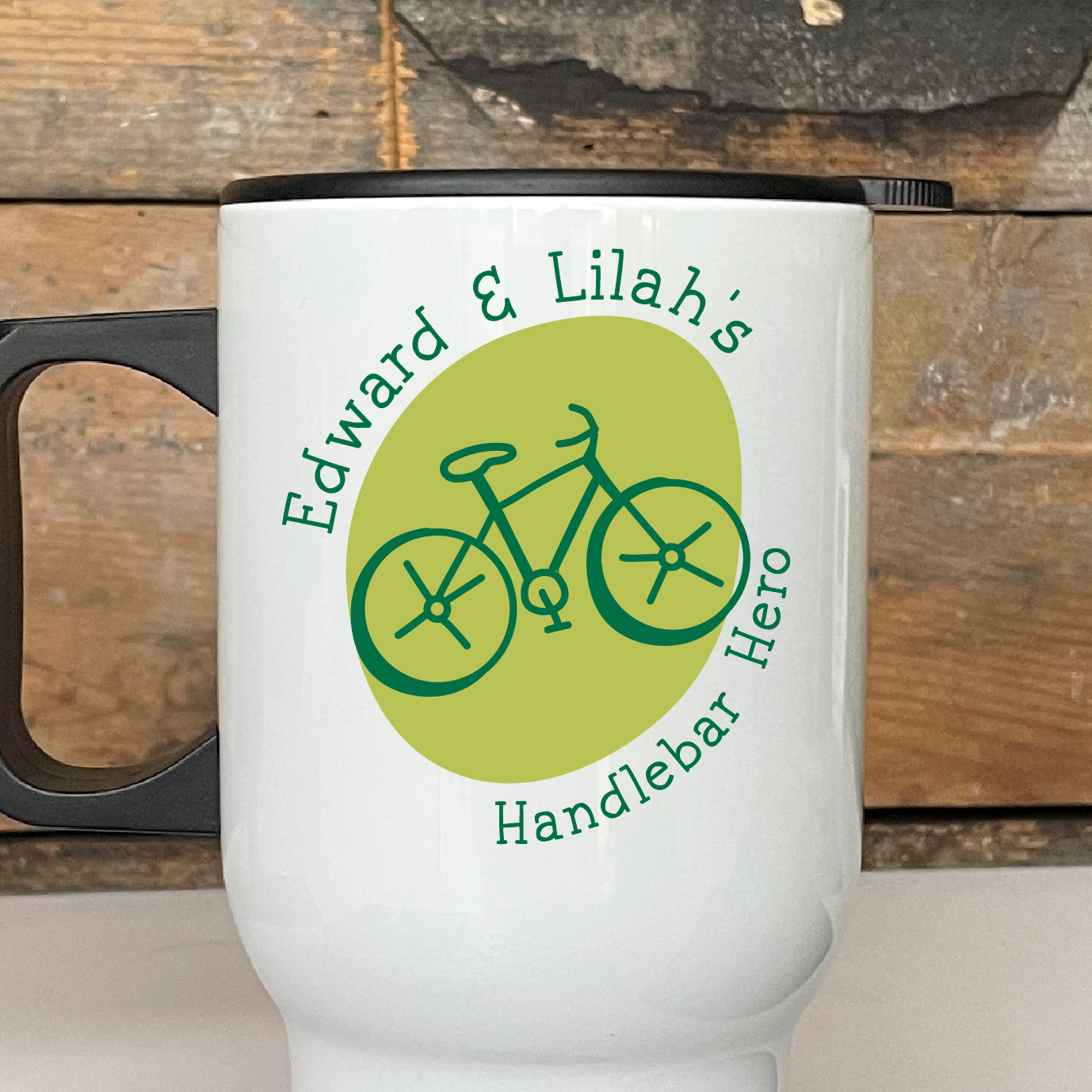 White travel mug with bicycle design and text on a wooden surface