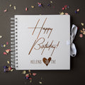 White spiral-bound notebook with 'Happy Birthday! Helens 30th!' text on a dark background with dried flowers.