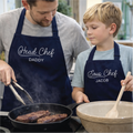 Man and young boy cooking together, wearing aprons labeled 'Head Chef Daddy' and 'Sous Chef Jacob'.