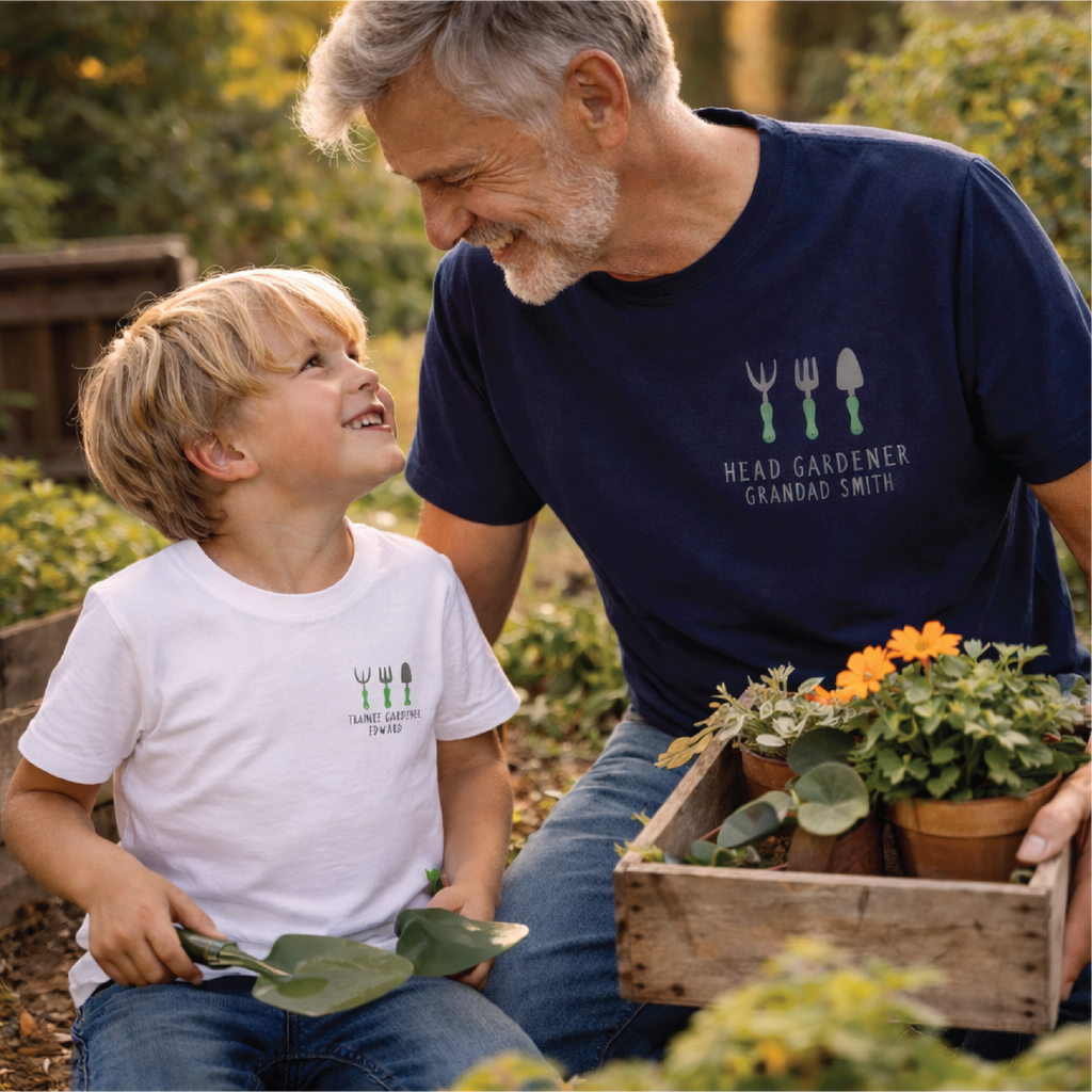 Man and child in a garden setting with potted plants, wearing matching t-shirts.