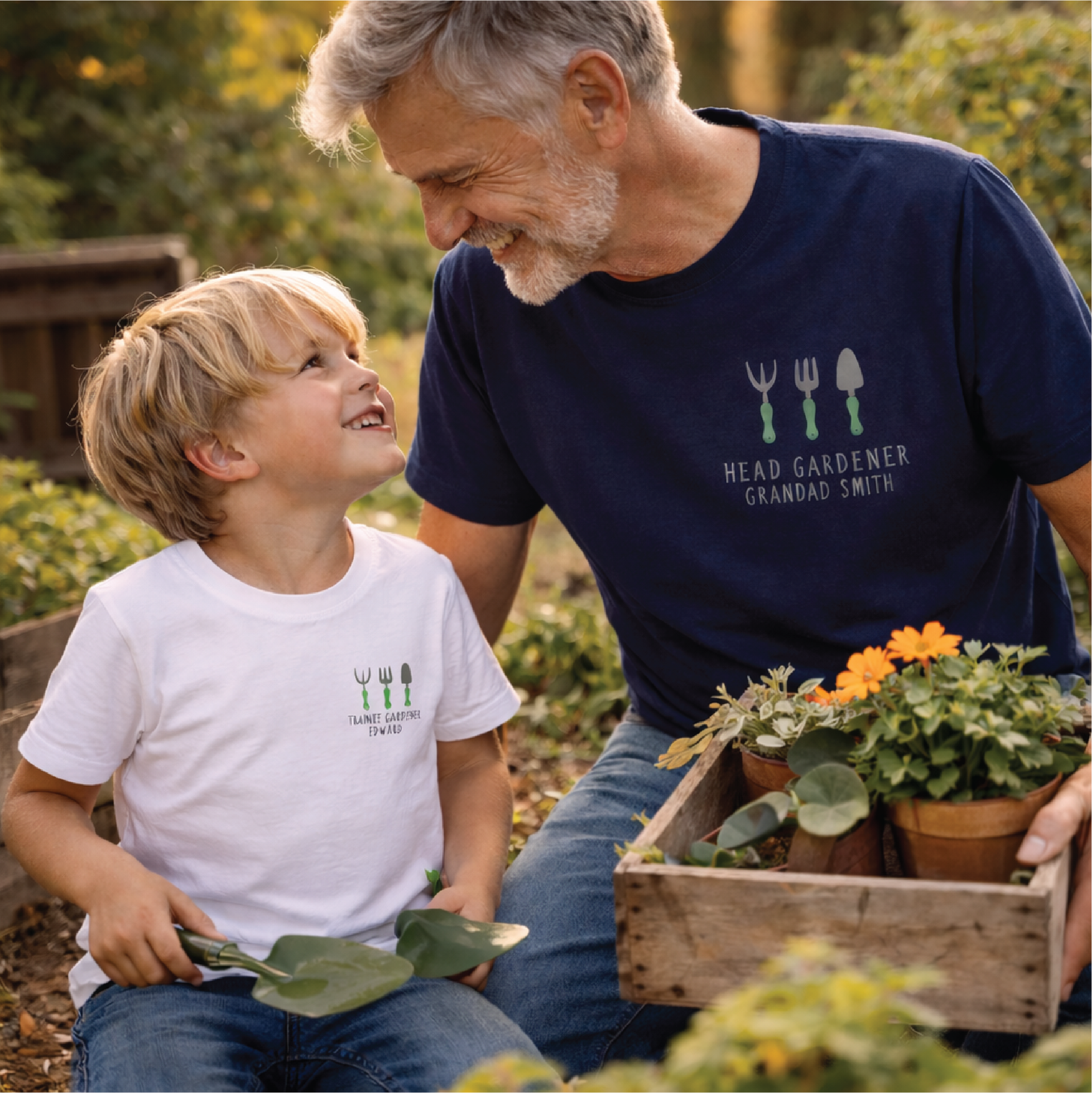 Man and child in a garden setting with potted plants, wearing matching t-shirts.