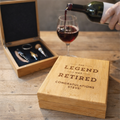 Wooden gift box with engraved text, wine glass, and bottle on a wooden surface.