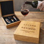 Wooden gift box with engraved text, wine glass, and bottle on a wooden surface.