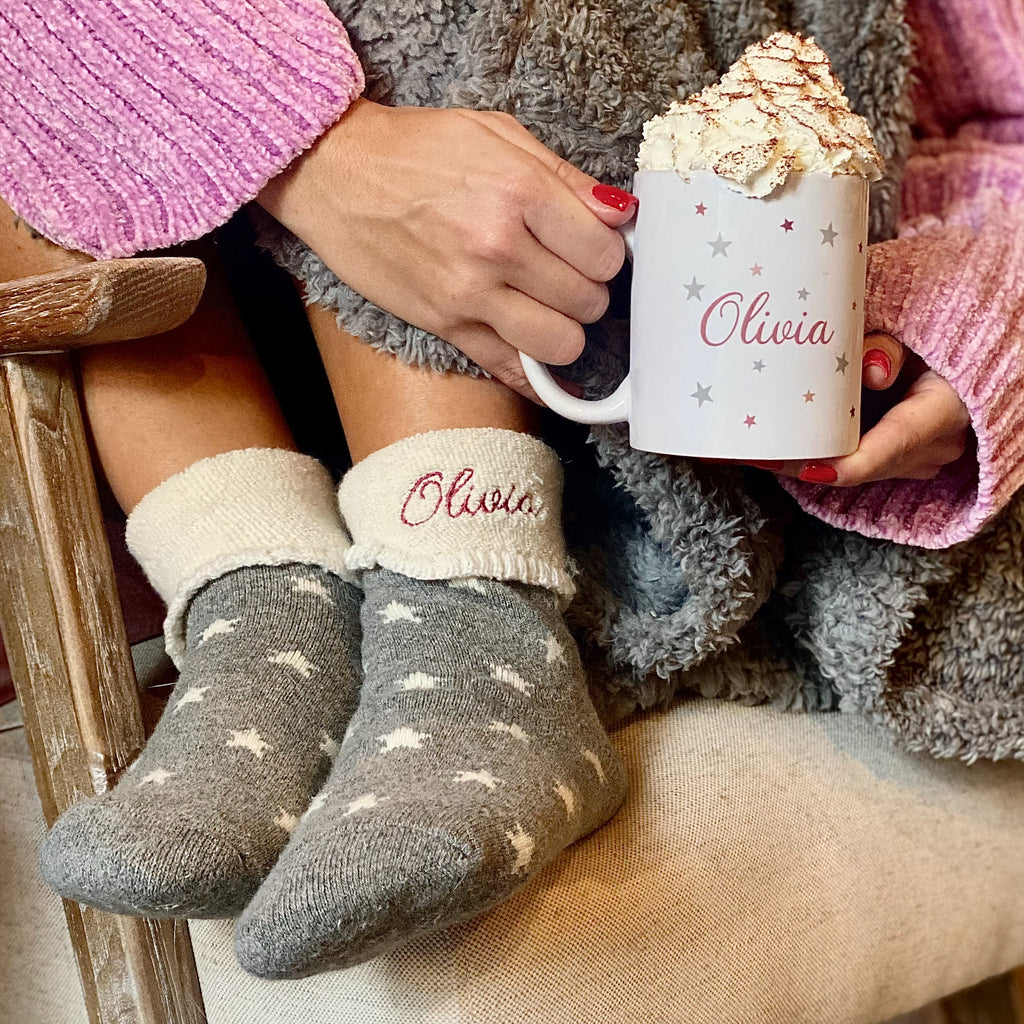 Person wearing socks with 'Olivia' on them, holding a mug with 'Olivia' printed on it.