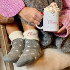 Person wearing socks with 'Olivia' on them, holding a mug with 'Olivia' printed on it.