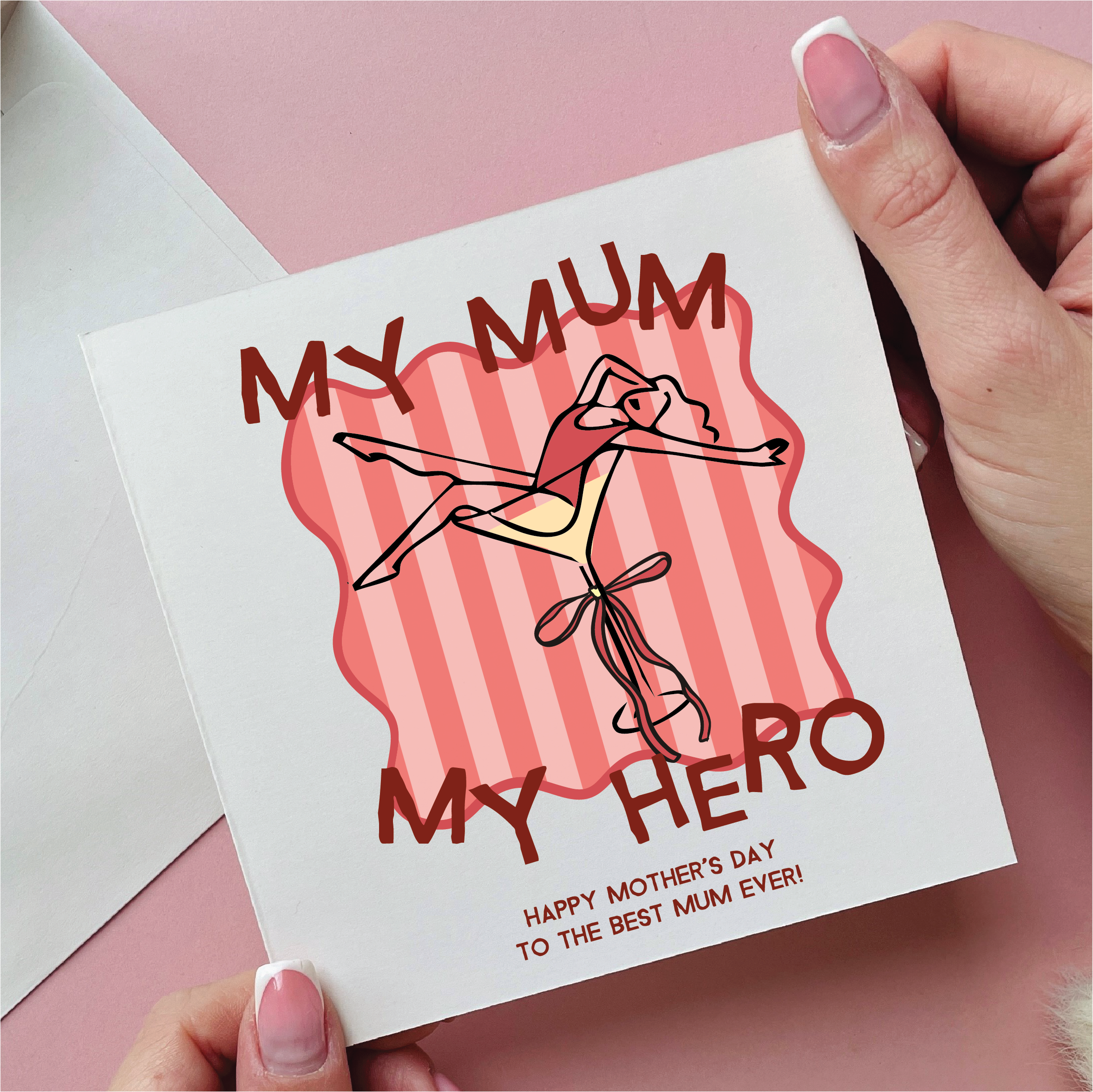 Card with 'My Mum, My Hero' text and illustration held by a hand on a pink background