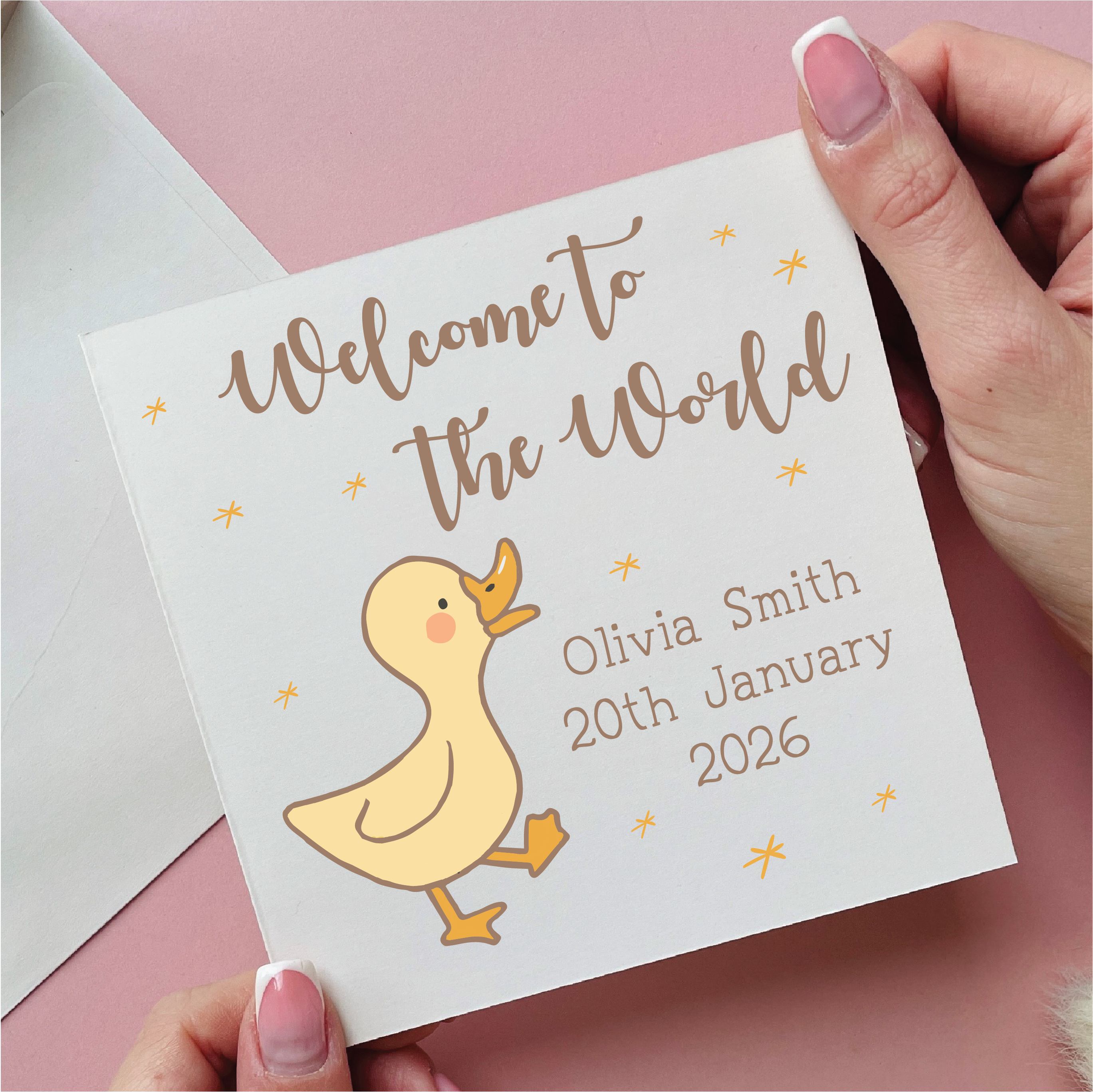 Card with 'Welcome to the World' text and a duck illustration, held by a hand on a pink background.