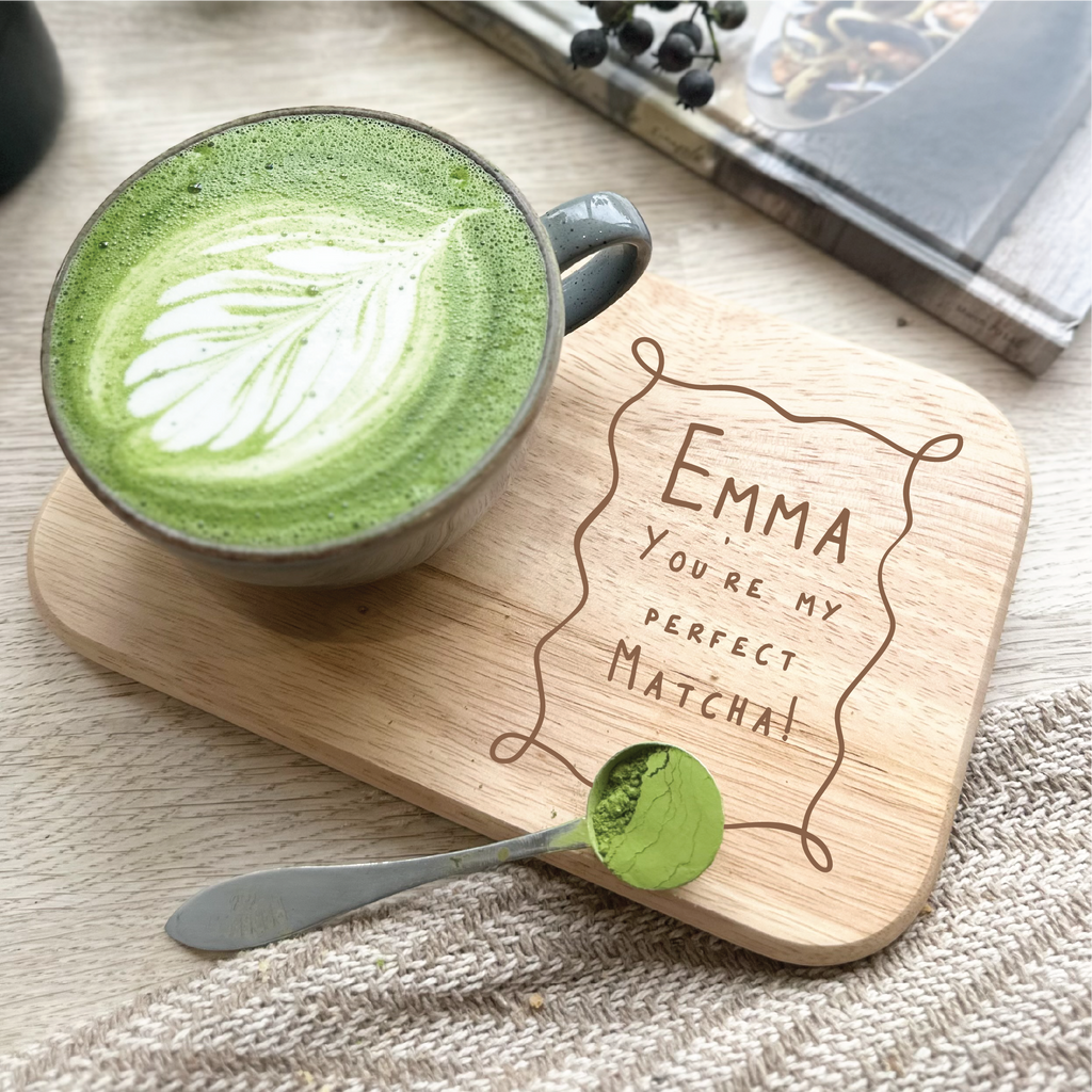 Green matcha latte with a wooden coaster and spoon on a textured surface