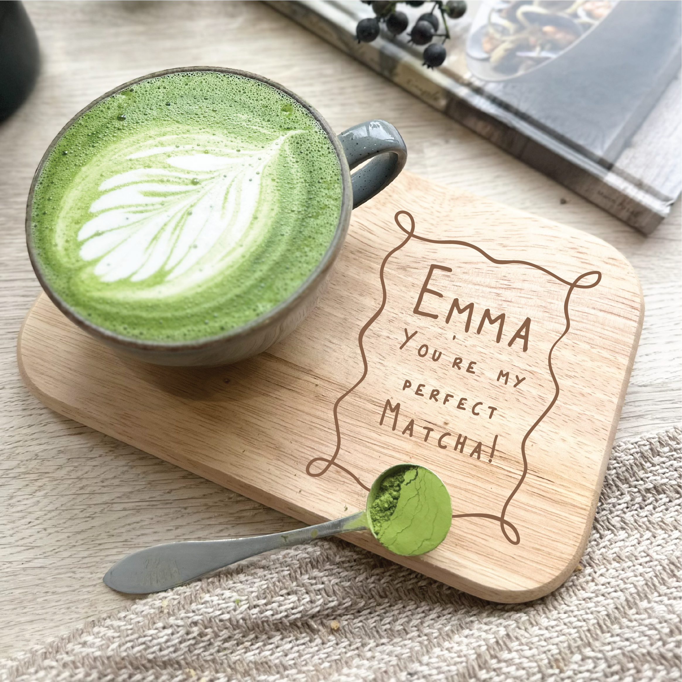 Green matcha latte with a wooden coaster and spoon on a textured surface