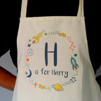 White apron with space-themed design and 'H is for Harry' text