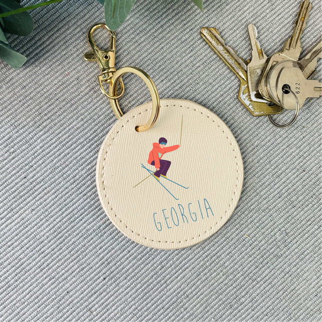 Round keychain with skiing design and 'Georgia' text on a textured surface