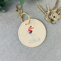 Round keychain with skiing design and 'Georgia' text on a textured surface