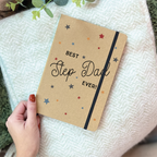 Notebook with 'Best Step Dad Ever!' text held by a hand on a textured surface.