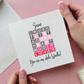 Card with text and hands holding it on a pink background