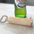 Wooden bottle opener with 'Happy 60th Paul' engraving in front of a Peroni beer bottle.