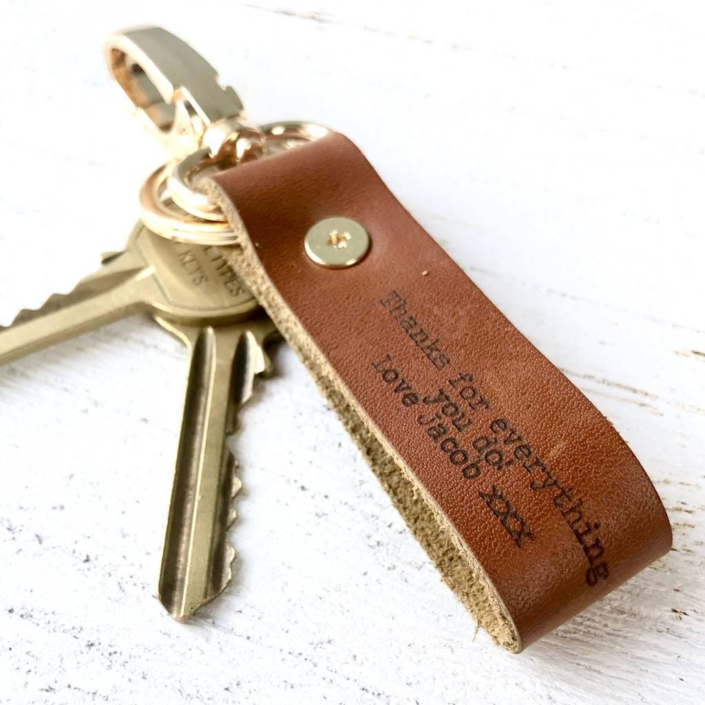 Brown leather keychain with engraved message on a white surface