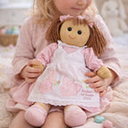 Child holding a personalized Easter doll with bunny design and text.