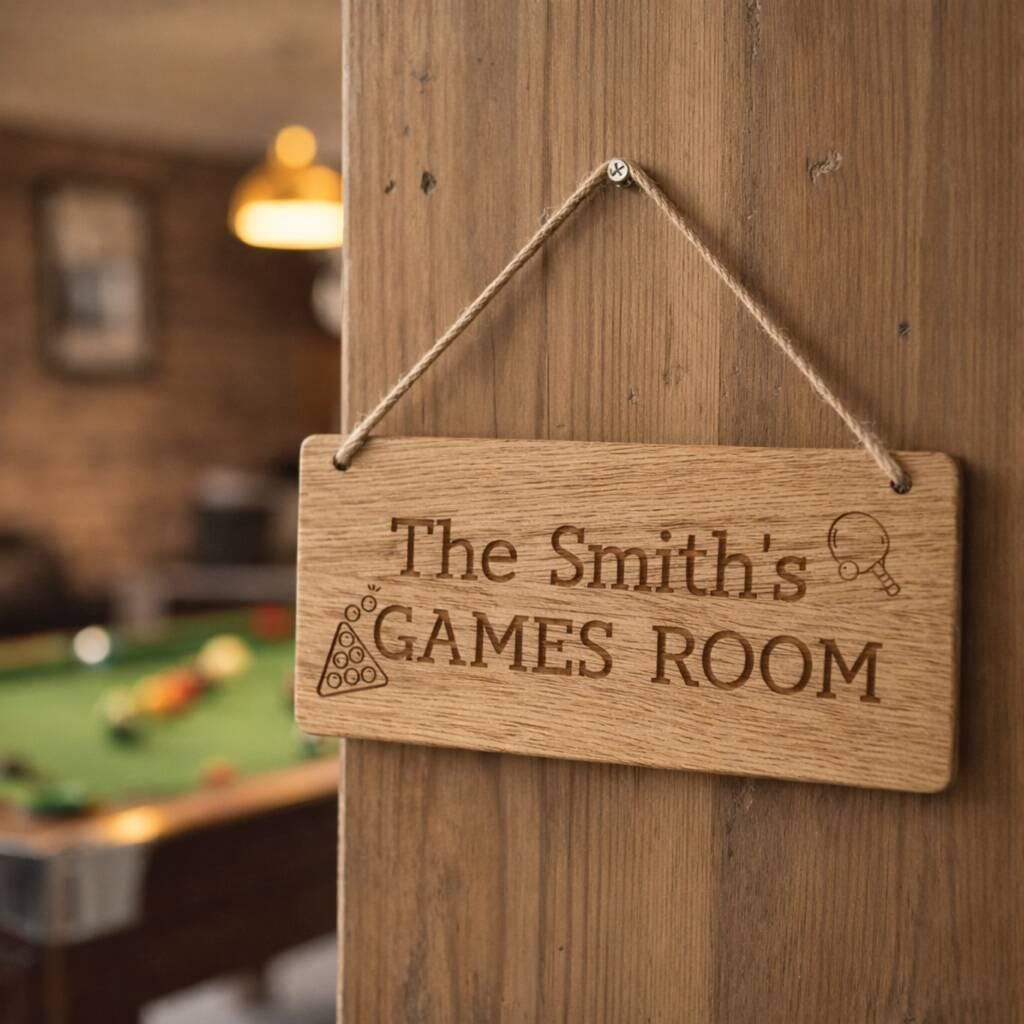 Wooden sign hanging on a door with 'The Smith's Games Room' engraved, pool table in the background.