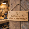 Wooden sign with 'Welcome to Dave's Workshop' text hanging on a wooden door.