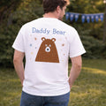 Man wearing a white t-shirt with 'Daddy Bear' design outdoors.