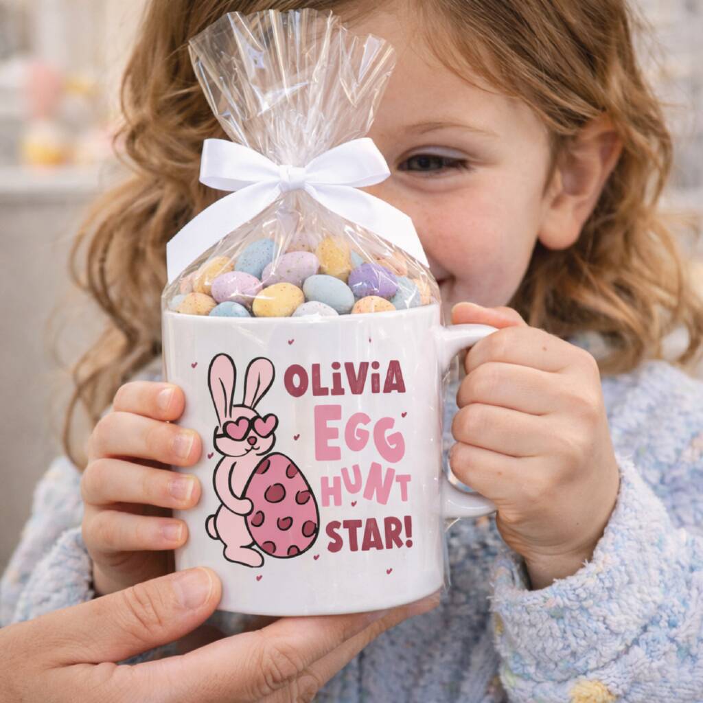 Child holding a mug with Easter design and candy, wearing a cozy outfit.