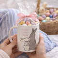 Person holding a 'Happy Easter Olivia' mug with a bag of candy and a bunny rabbit design.