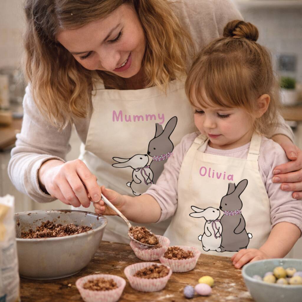 Woman and child in matching bunny aprons preparing food together in a kitchen