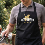 Man wearing a 'Meat Master' apron while grilling outdoors.
