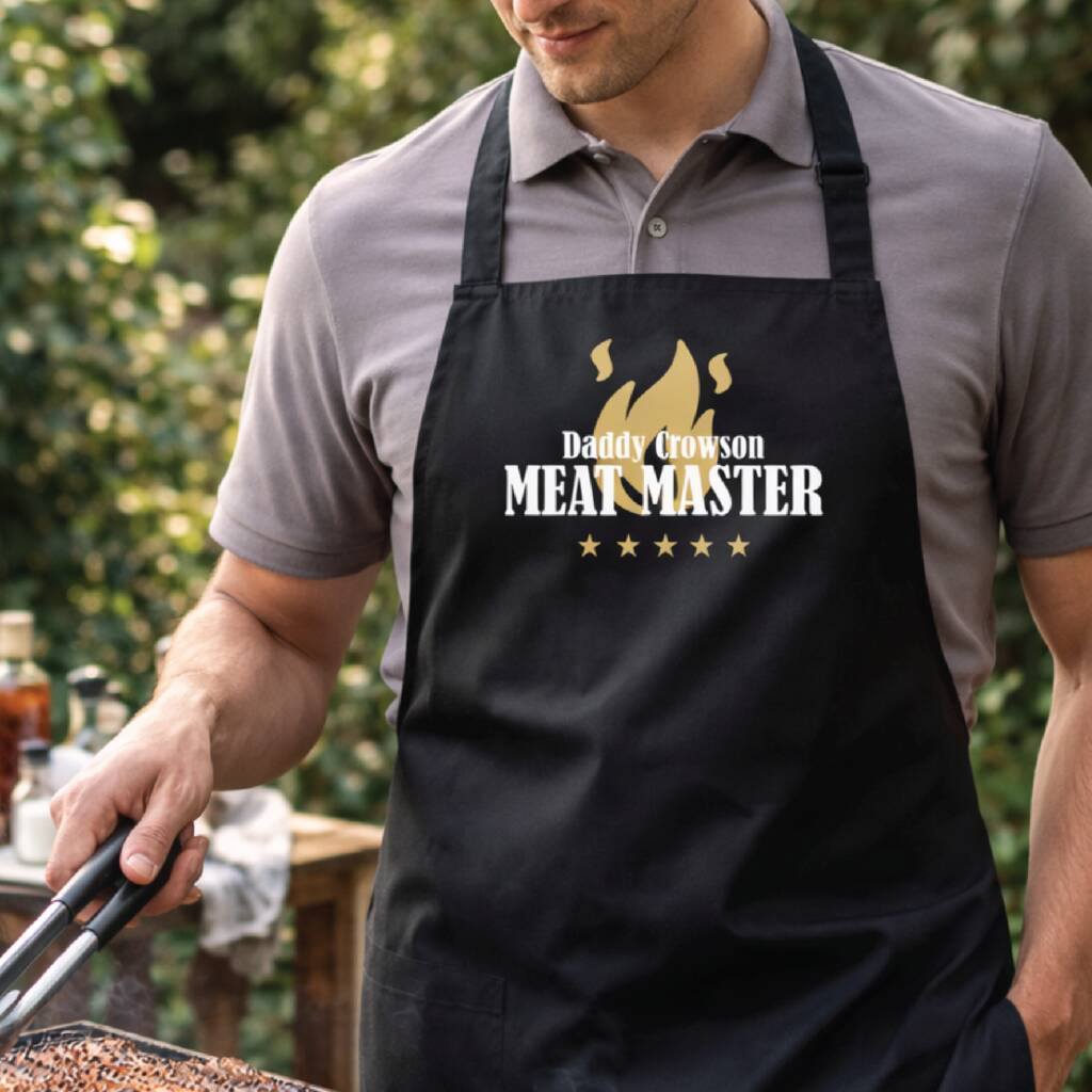 Man wearing a 'Meat Master' apron while grilling outdoors.