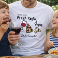 Man wearing a t-shirt with pizza, pasta, and wine design, holding a glass of red wine, surrounded by two children eating.
