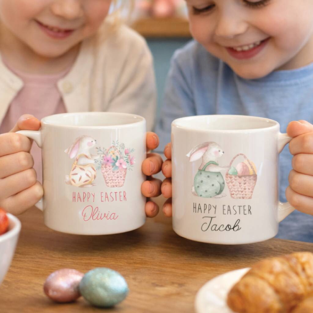 Two children holding personalized Easter mugs with names and illustrations.
